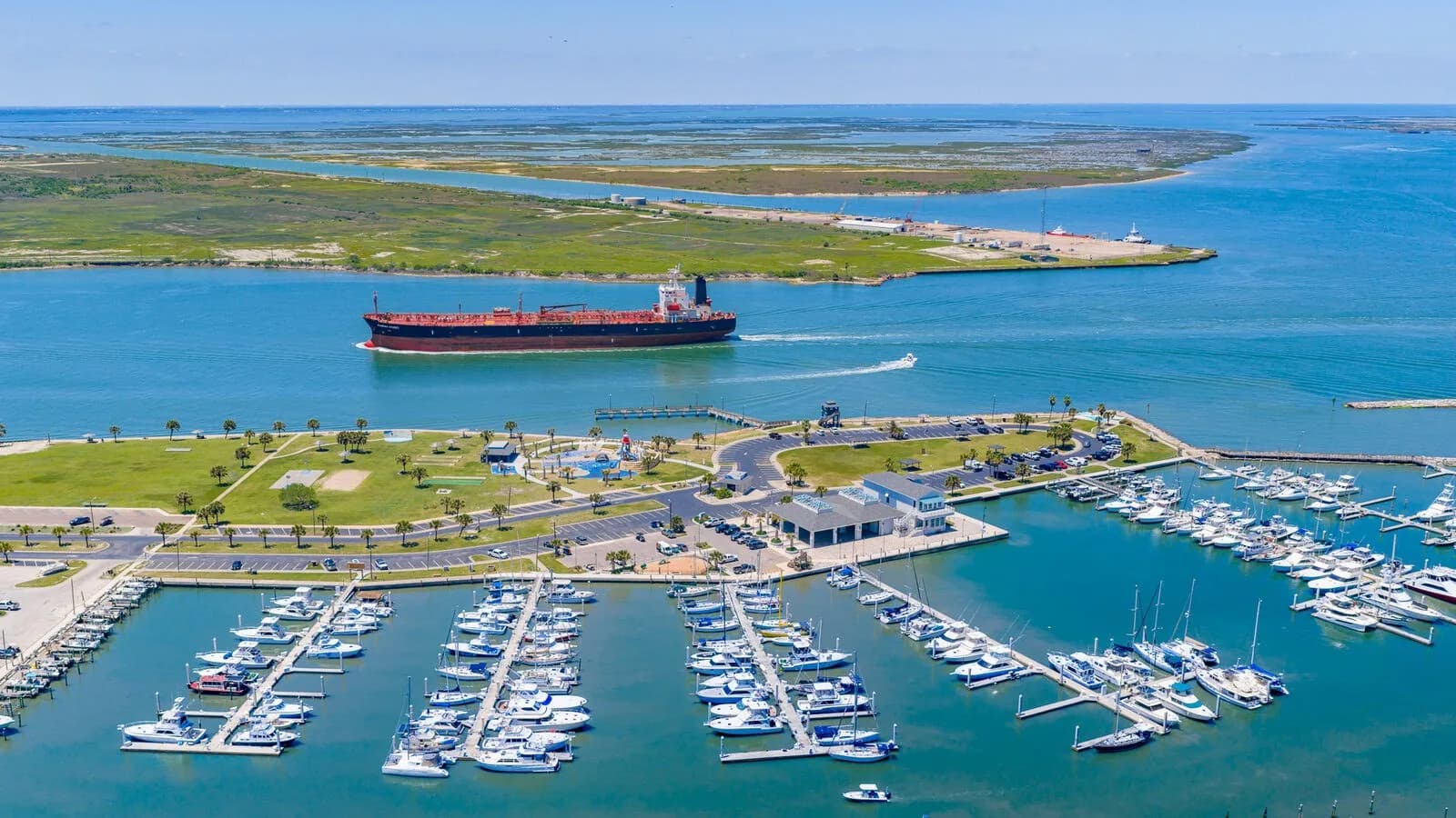 Aerial view of Port Aransas with a tanker passing through the Aransas Pass shipping channel above the marina and Roberts Point Park