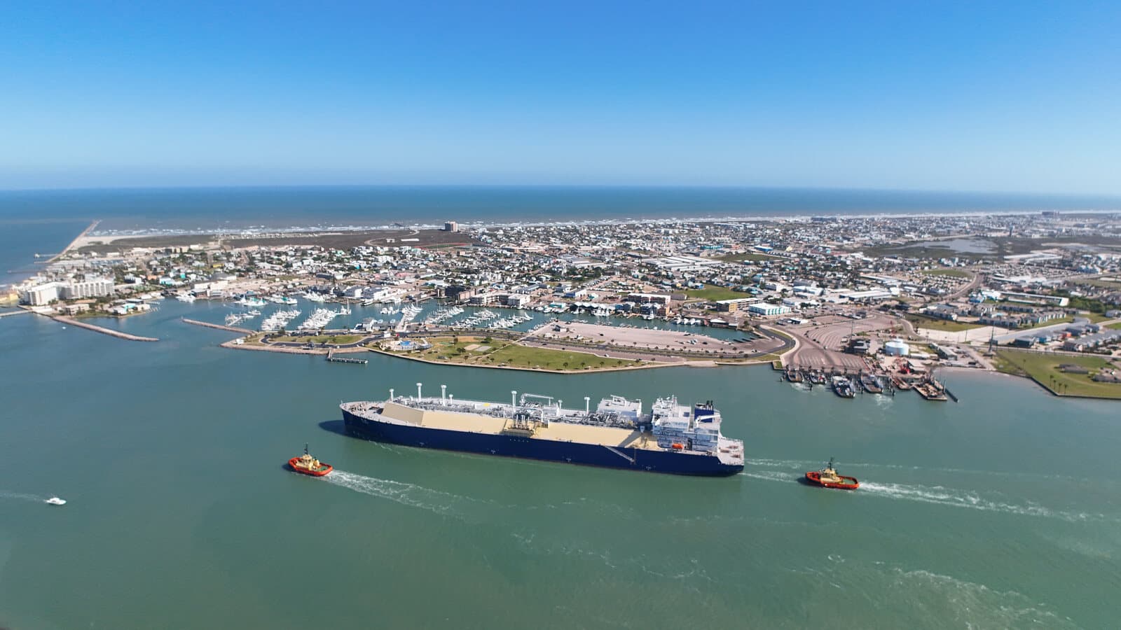 Aerial view of Port Aransas, Texas with the marina, barrier-island homes, Gulf beach, and ship channel visible from above - representative of the Mustang Island setting near Cinnamon Shore.