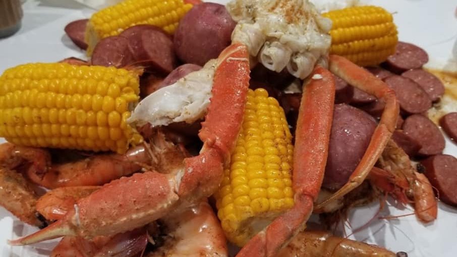 Hungry Cajun seafood boil with shrimp, snow crab legs, corn, sausage, and potatoes on butcher paper at The Crazy Cajun in Port Aransas